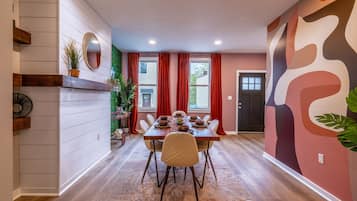 A dining area with a wooden table set for four, surrounded by chairs.