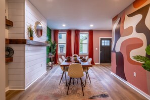 Un coin repas avec une table en bois, dressée pour quatre personnes, entourée de chaises.