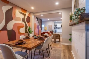 A dining area with a wooden table set for a meal, surrounded by chairs.