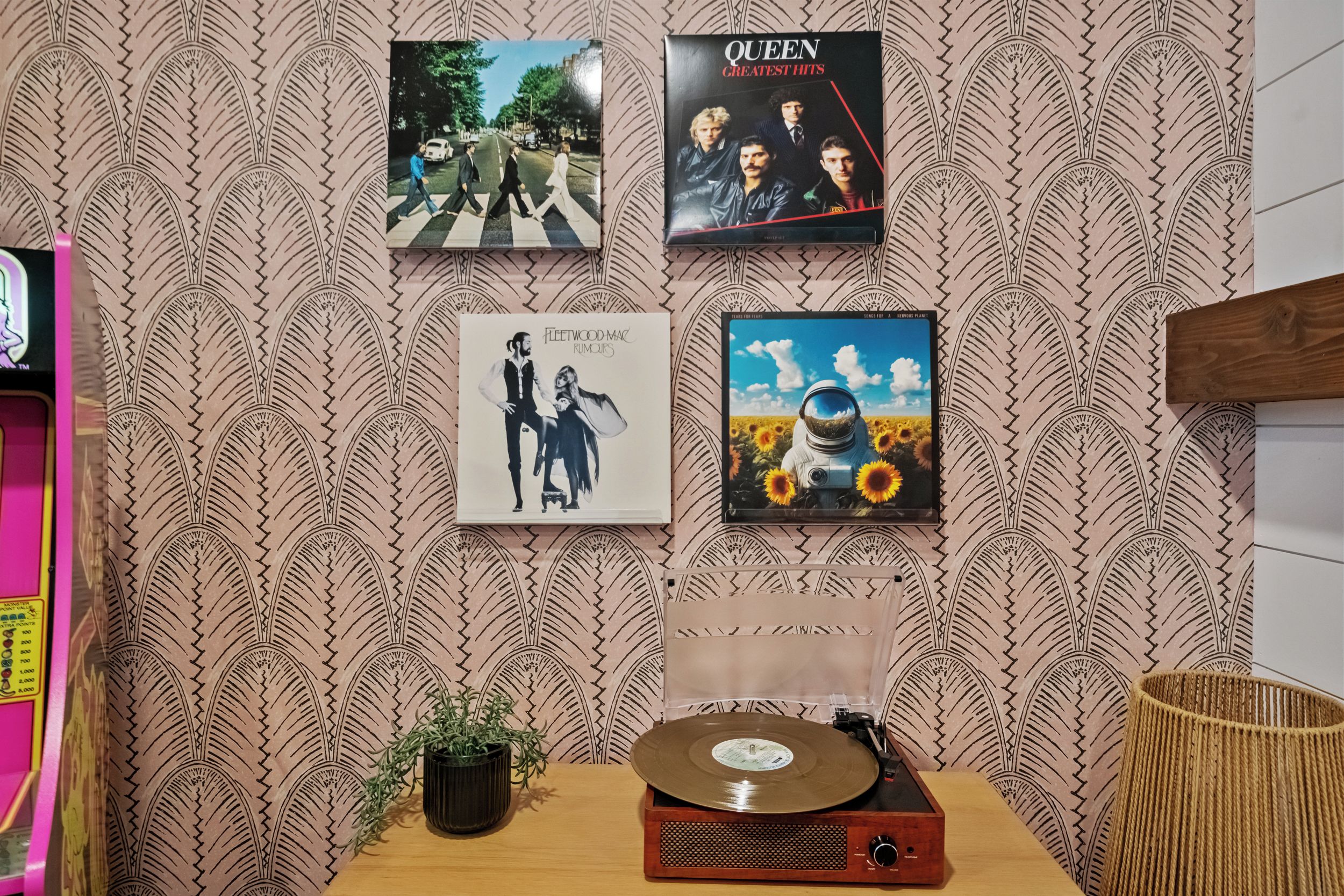 A wall with four framed pictures, a turntable, and a small plant.
