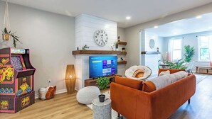 A living room with a TV, sofa, and arcade game.