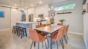 Una cocina moderna con una isla central, taburetes de bar y una mesa de comedor con sillas.