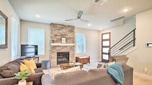 Una sala de estar con chimenea, televisor y escalera.