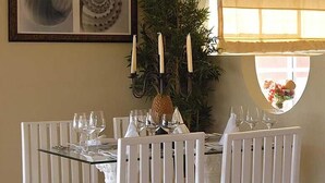 A dining table set with white chairs, a glass top, and multiple wine glasses. -  Dream Holidays Vacation (Puerto Plata)