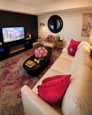 A living room with a sofa, a coffee table with flowers, a TV, and a fireplace.
