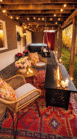 Une terrasse extérieure aménagée avec des meubles en osier, un foyer et un jacuzzi.