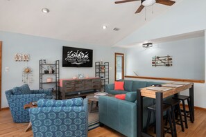 A modern living room with a television, seating area, and a dining table.