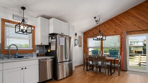 Eine moderne Küche mit Edelstahlgeräten, Holzboden und einem Essbereich mit Tisch und Stühlen.