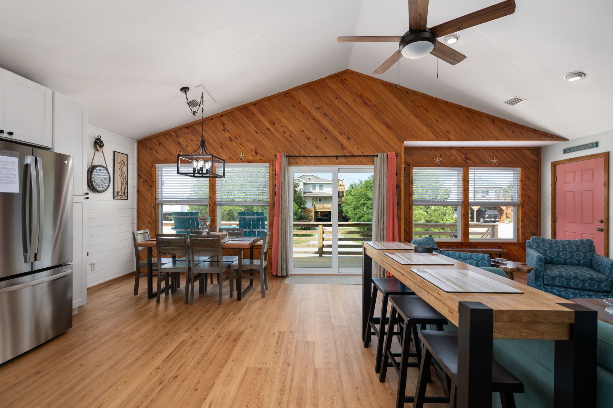 A modern kitchen with a wooden ceiling, a dining area with a table and chairs, and a view of the outside.