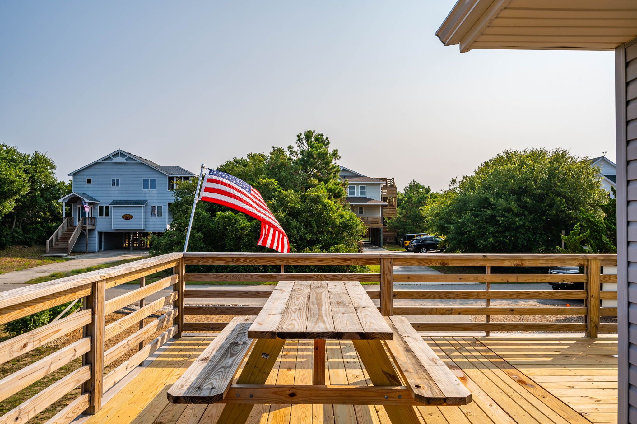 Une terrasse en bois avec une table de pique-nique et un drapeau américain.
