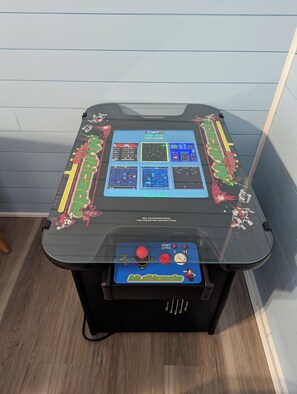 A gaming arcade table with a control panel and a screen displaying game options. - Just Wright: Heated Pool, Soundside, close to beach & sound! (Kitty Hawk)