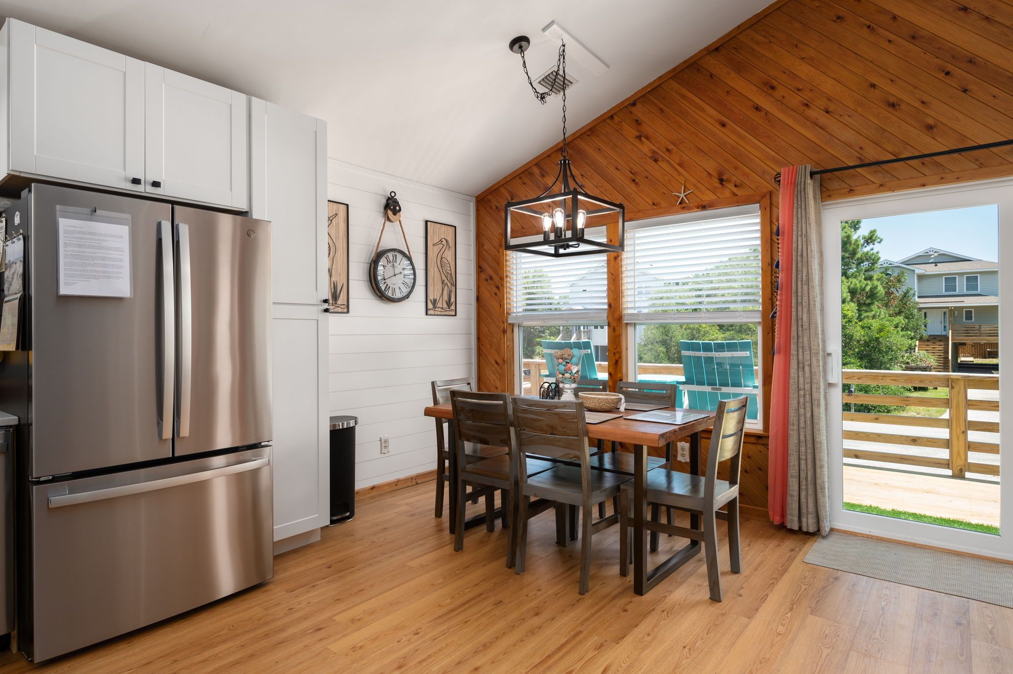 A modern kitchen with a stainless steel refrigerator, wooden cabinets, and a dining area with a table and chairs.