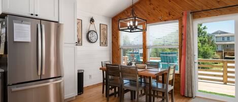 A modern kitchen with a stainless steel refrigerator, wooden cabinets, and a dining area with a table and chairs.