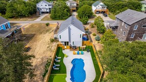 Ein Wohngebiet mit einem großen Haus, das einen Pool, eine Terrasse und einen umzäunten Garten hat.