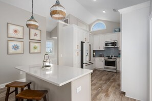 A modern kitchen with white cabinetry, a central island, and pendant lighting.