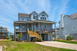 A two-story residential building with a covered front porch and a small outdoor seating area.