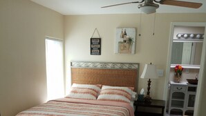 A bedroom with a bed, a nightstand, a chair, a ceiling fan, a wall-mounted lamp, and a mirror. - Charm remodeled 2b 2b with 2/p space only 7 minutes from down town (Tucson)