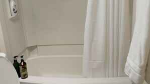A bathroom with a white toilet, a bathtub with a white shower curtain, and a blue bath mat. - Charm remodeled 2b 2b with 2/p space only 7 minutes from down town (Tucson)