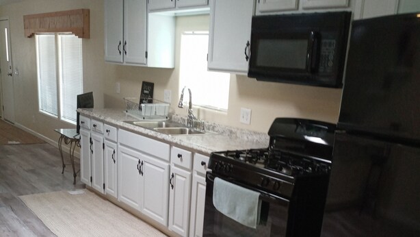 A kitchen with white cabinets, a black refrigerator, a stove, and a microwave. - Charm remodeled 2b 2b with 2/p space only 7 minutes from down town (Tucson)