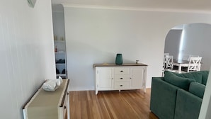 Ein Zimmer mit Holzboden, einem grünen Sofa, einem weißen Schrank und einem kleinen Tisch mit einer Vase.