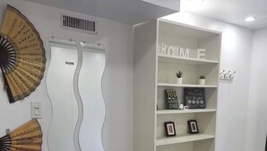 A room with a white bookshelf, a decorative fan, and a mirror with a wavy design. - Cozy 1 bedroom Appartment  minutes away from Ajax Waterfront. (Ajax)