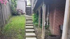A concrete pathway leading to a brick house with a wooden fence and steps. - Cozy 1 bedroom Appartment  minutes away from Ajax Waterfront. (Ajax)