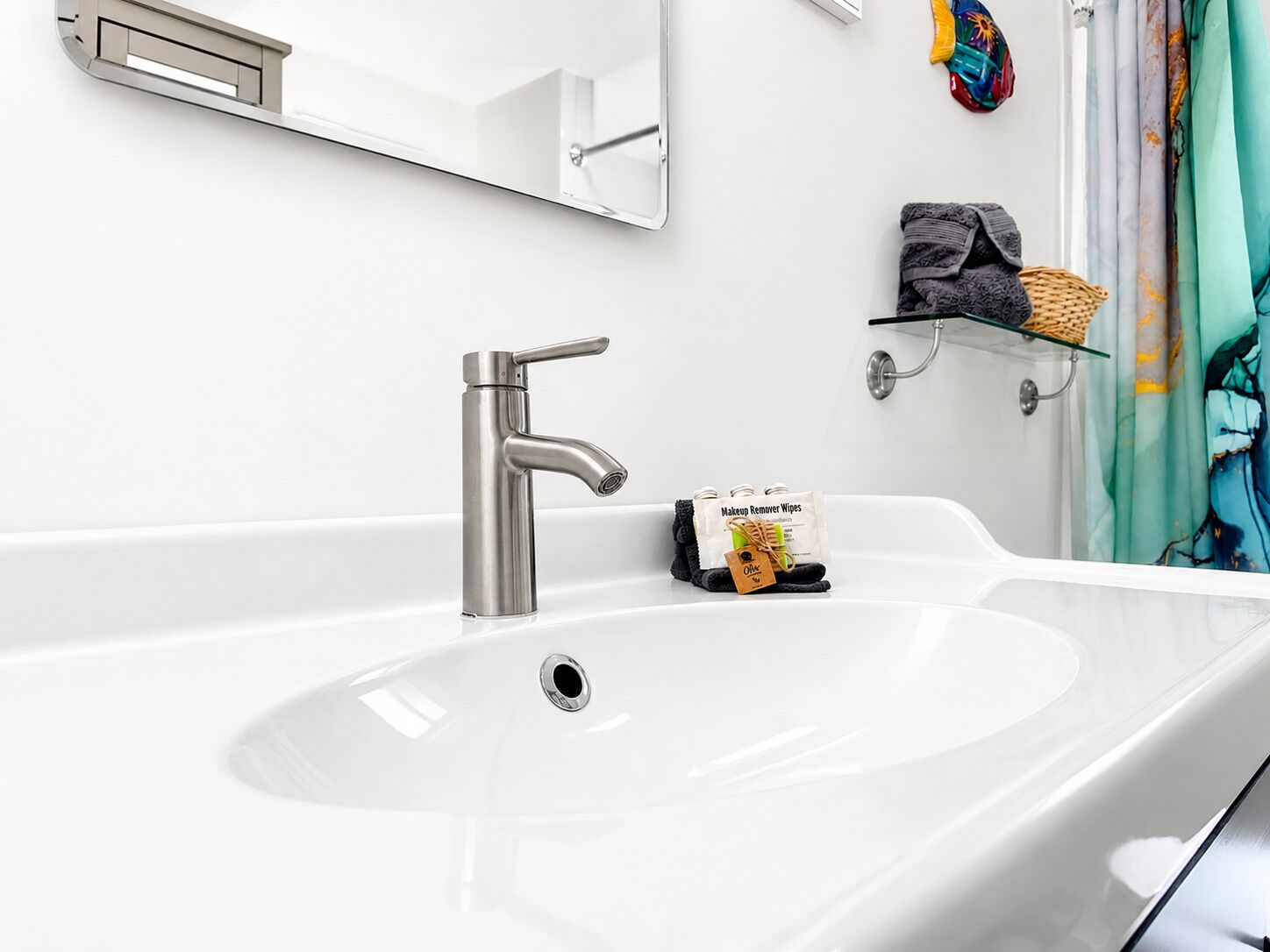 Un baño moderno con un lavamanos grande de color blanco, un grifo cromado, un espejo sobre el lavamanos y una repisa con artículos de aseo.