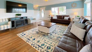 A living room with a brown leather sofa, a striped armchair, a coffee table, and a TV mounted on the wall.