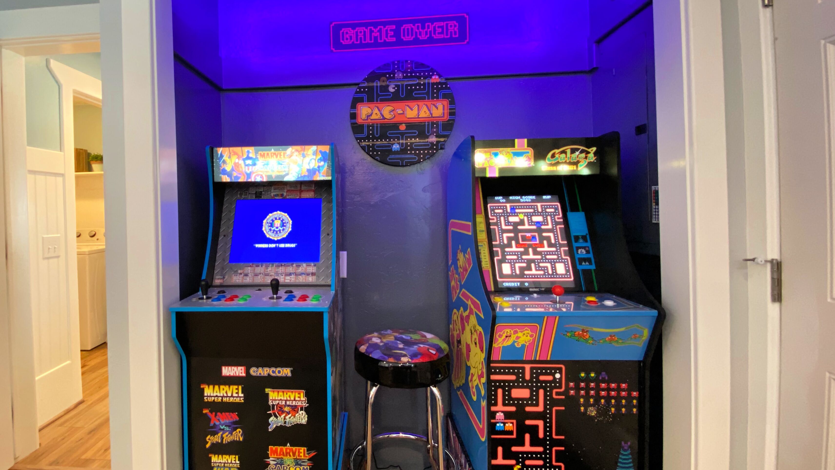A room with arcade machines, including Pac-Man and other games, and a sign that says "GAME OVER".