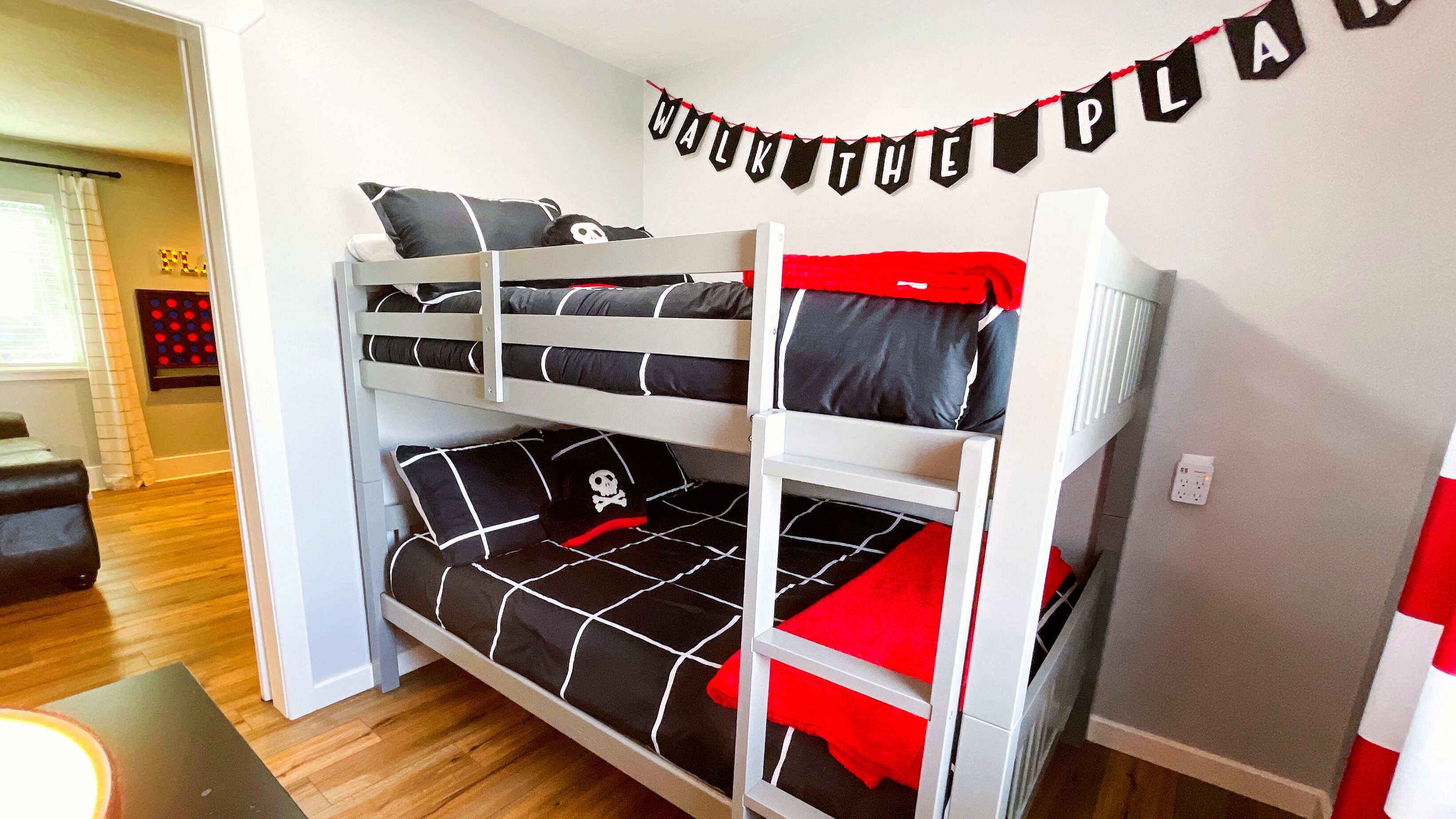 A bunk bed with a pirate-themed pillow and a 'WALK THE PATH' banner.
