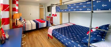 A bunk bed room with a nautical theme, featuring anchor-patterned bedding and red and white striped curtains.