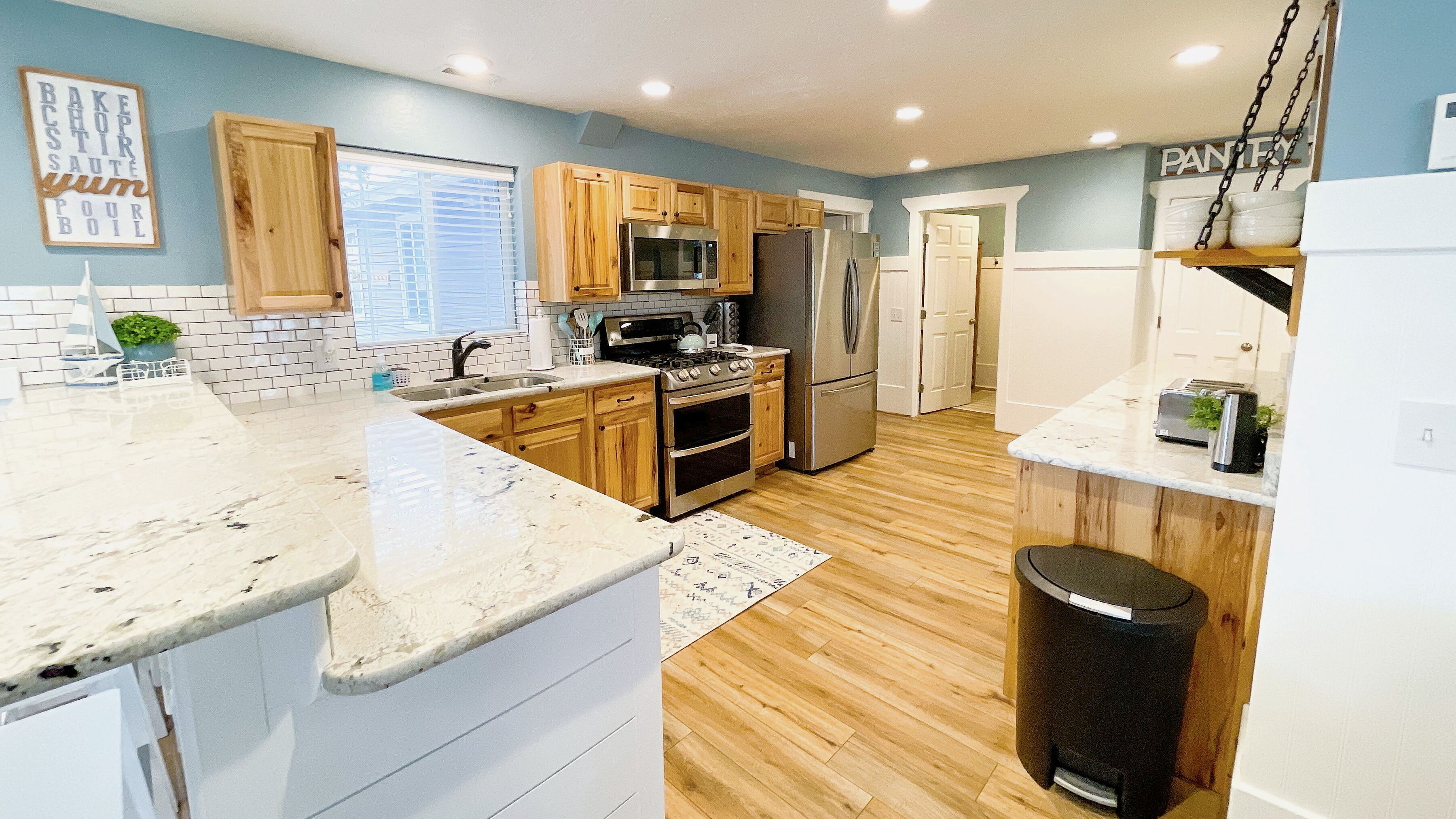A modern kitchen with wooden cabinets, stainless steel appliances, and a marble countertop.