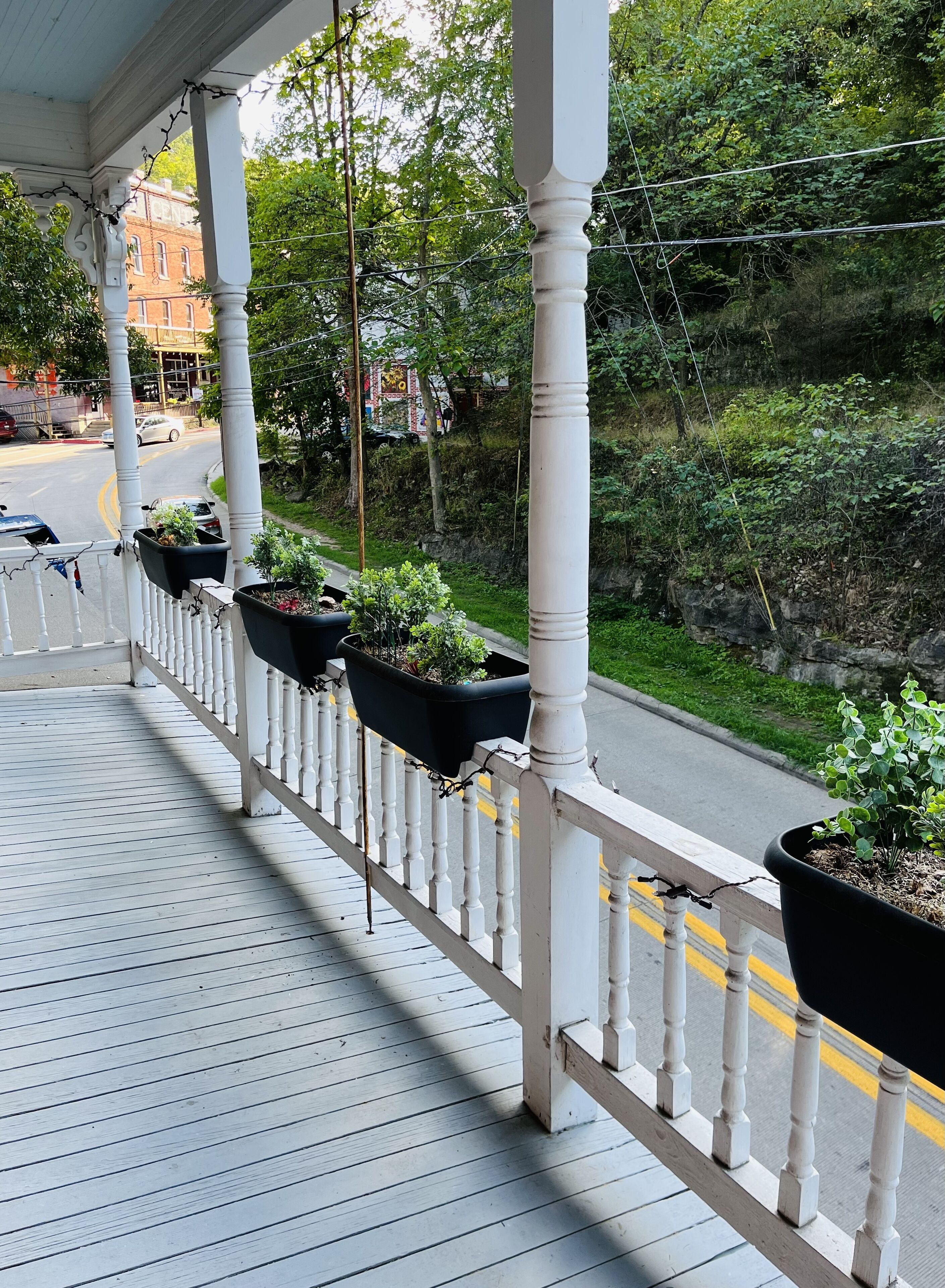 A covered porch with white balustrades and black planters.