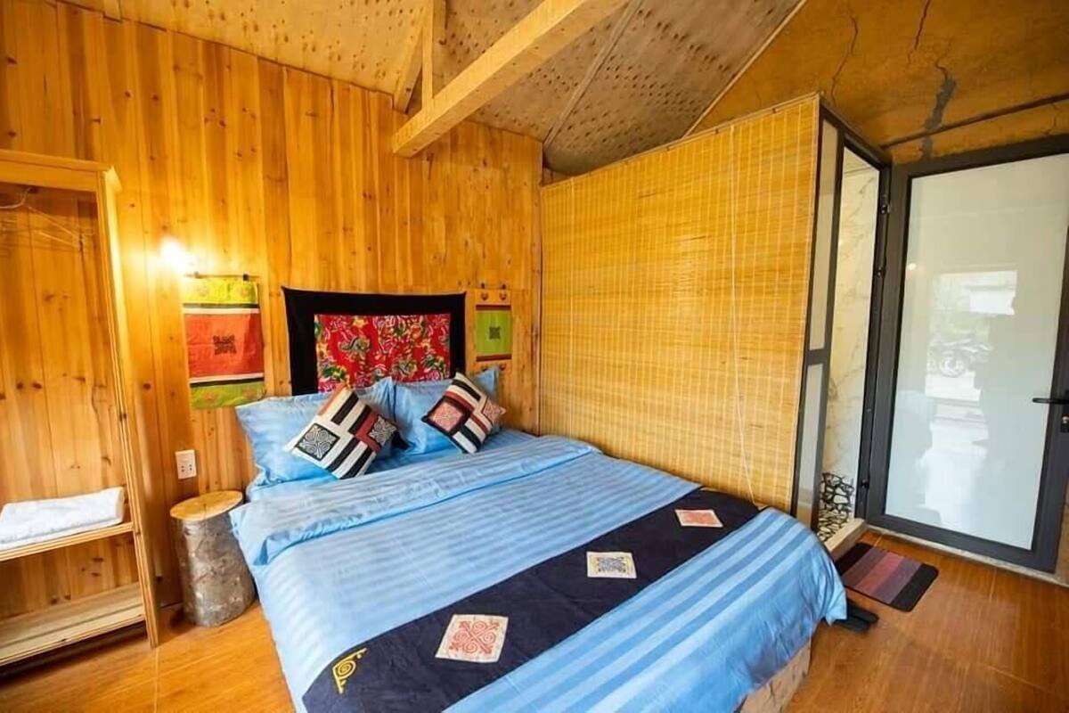 Ein Zimmer mit Holzboden, einem Bett, einem kleinen Tisch und einer Schiebeglastür.