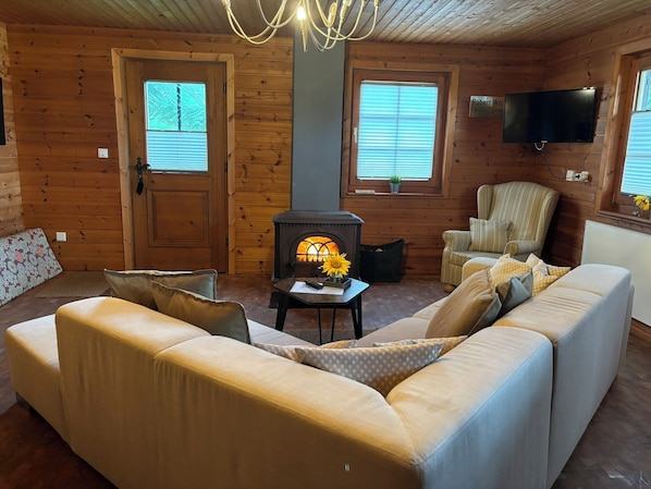 A cozy log cabin interior with a sofa, armchair, and a fireplace.