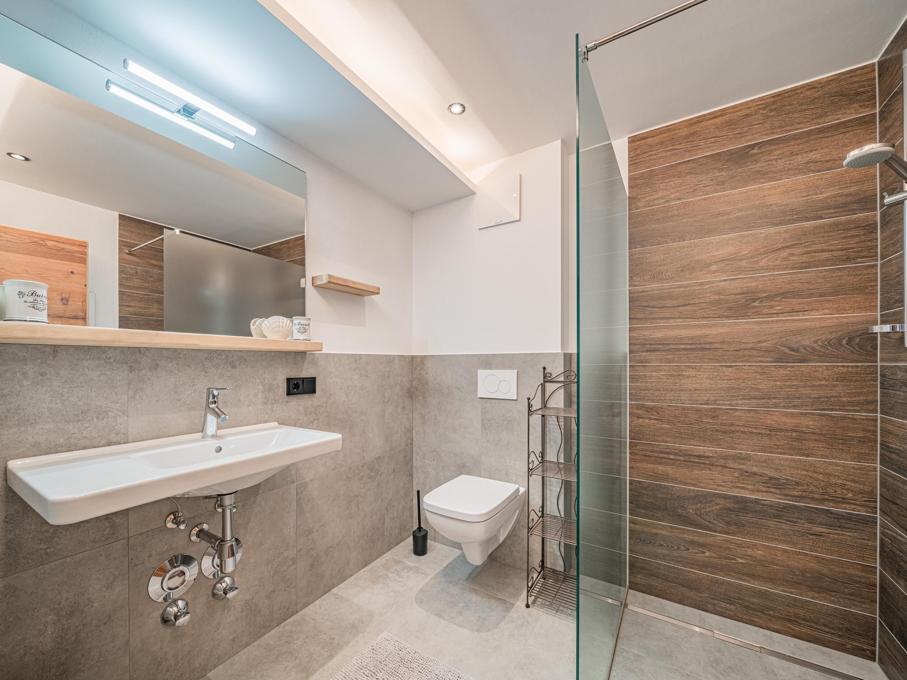 Une salle de bain moderne avec une douche à parois de verre, un lavabo blanc et des toilettes.