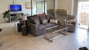 A modern living room with a sofa, armchair, coffee table, and a TV.