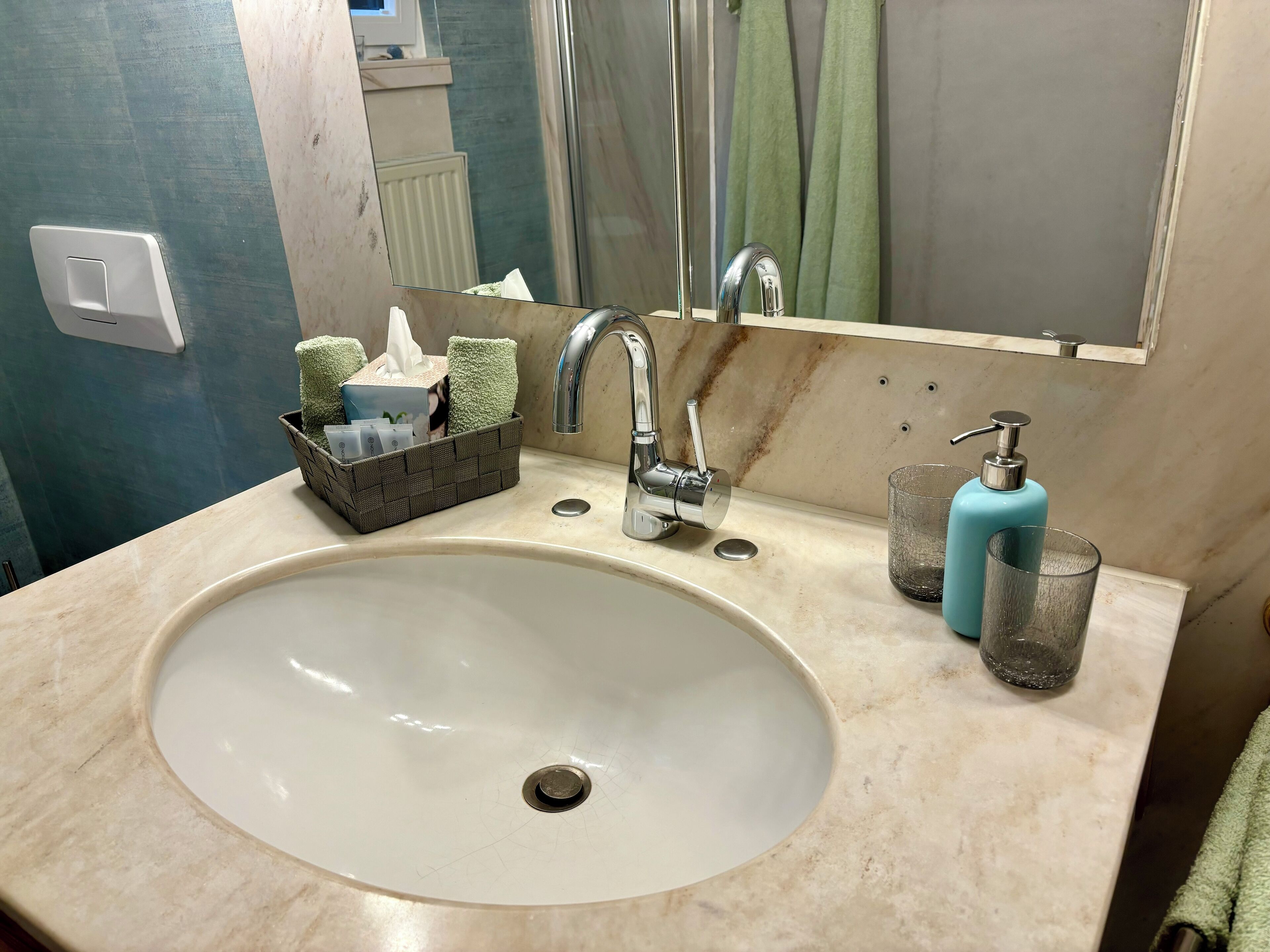 A bathroom sink with a mirror, a soap dispenser, and a tissue box.