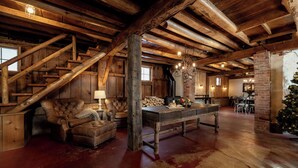 A rustic interior with exposed wooden beams, a fireplace, a dining area, and a Christmas tree.