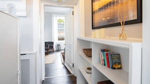 A hallway with a bookshelf, a framed picture, and a door leading to another room.