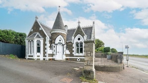 A stone building with a pointed roof and arched windows, likely a historical or religious structure.