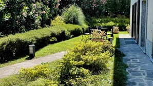 A well-maintained garden with a stone pathway leading to a seating area with tables and chairs.