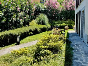 A well-maintained garden with a stone pathway leading to a seating area with tables and chairs.