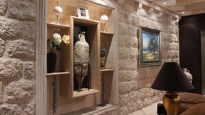 Un mur intérieur en pierre, agrémenté d’étagères intégrées où sont exposés des objets décoratifs et un tableau.