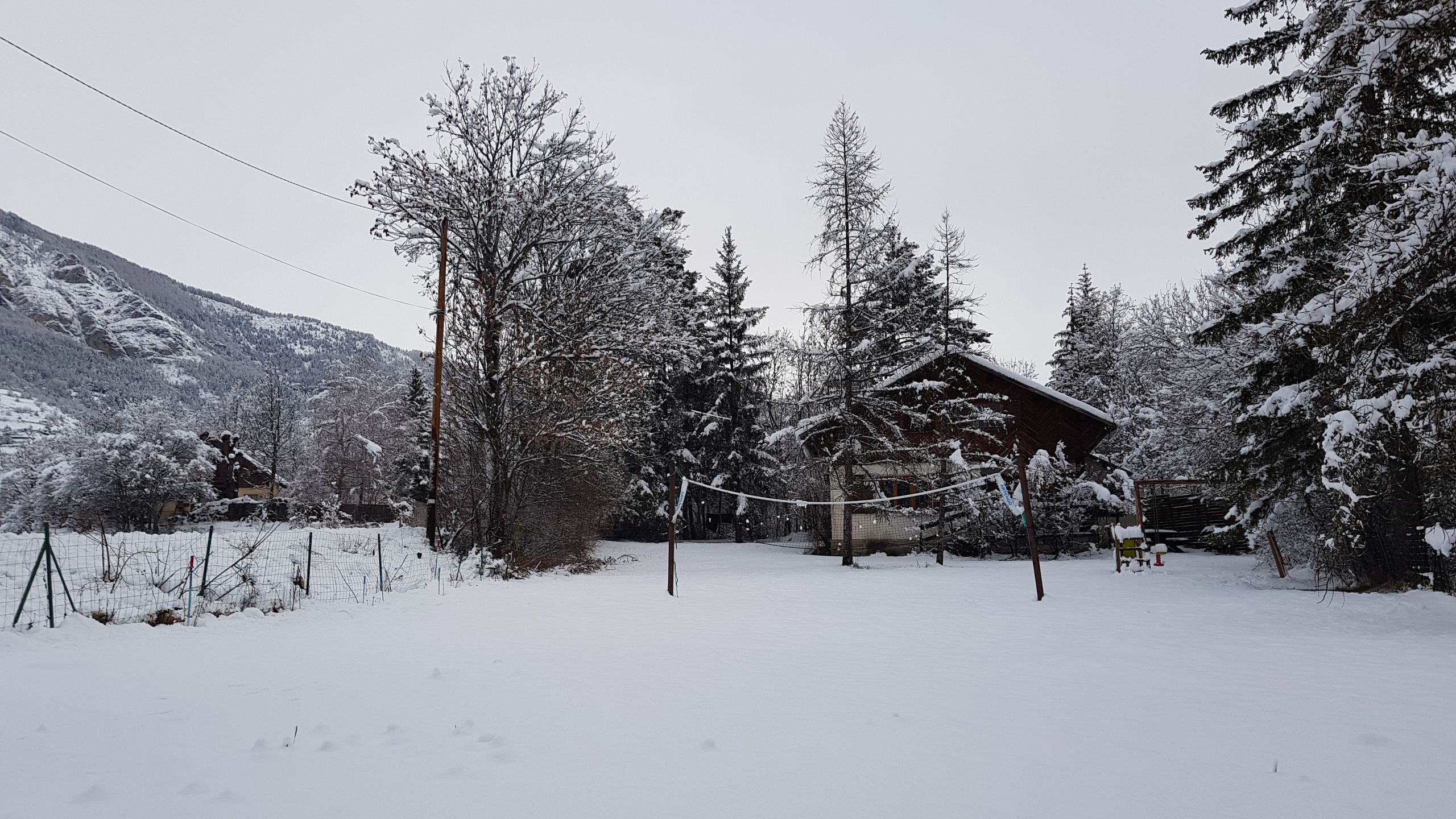 A cabin surrounded by snow-covered trees and a mountain in the background.