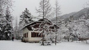 A snow-covered cabin with a wooden exterior, surrounded by snow-laden trees and a hilly backdrop. - Attractive family chalet sleeps 10 to 12 in Val d'Allos (Villars-Colmars)