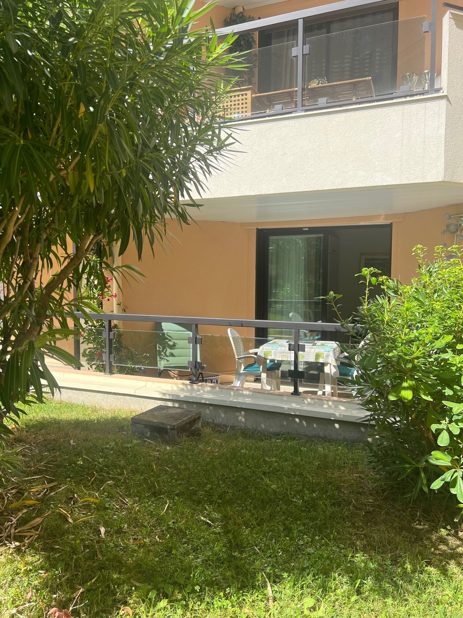 Un balcon agrémenté d’une table et de chaises, entouré de verdure.