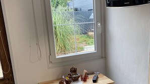 Eine kleine Küche mit Fenster, einem Tisch mit zwei Hocker und einem an der Wand montierten Samsung TV.