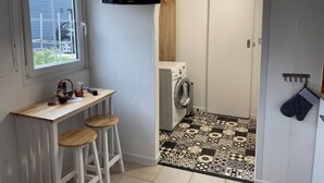 Ein Waschraum mit einer Waschmaschine, einem darüber montierten Fernseher und einem gemusterten Boden.
