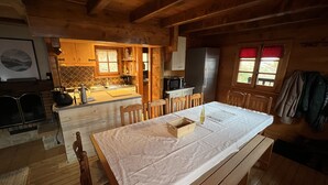 A cozy cabin-style kitchen with wooden cabinets, a dining table, and a bench. - Individual cottage 10-12 person  (Châtel)